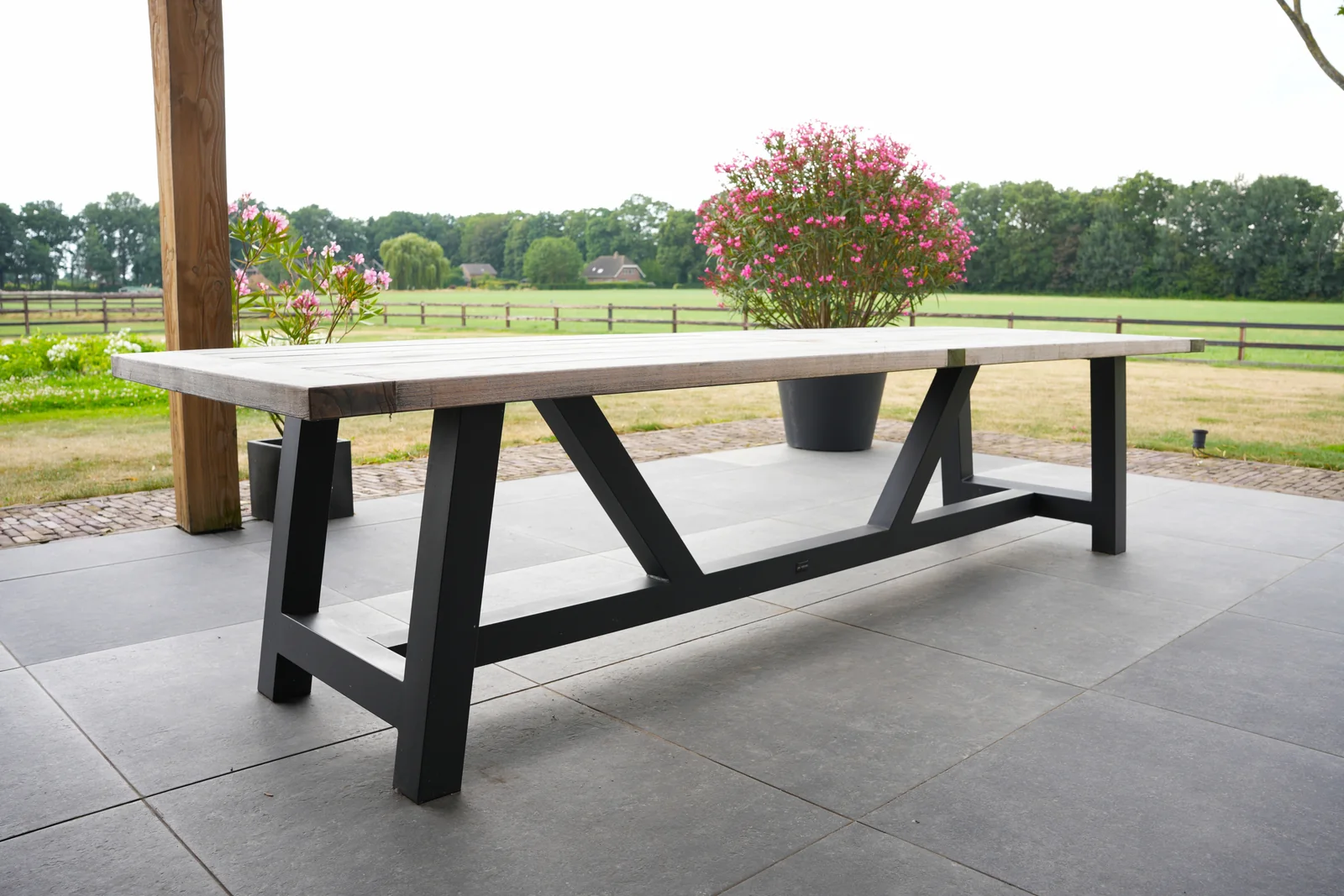 Buitentafel met houten blad en zwart stalen onderstel vanaf de zijkant