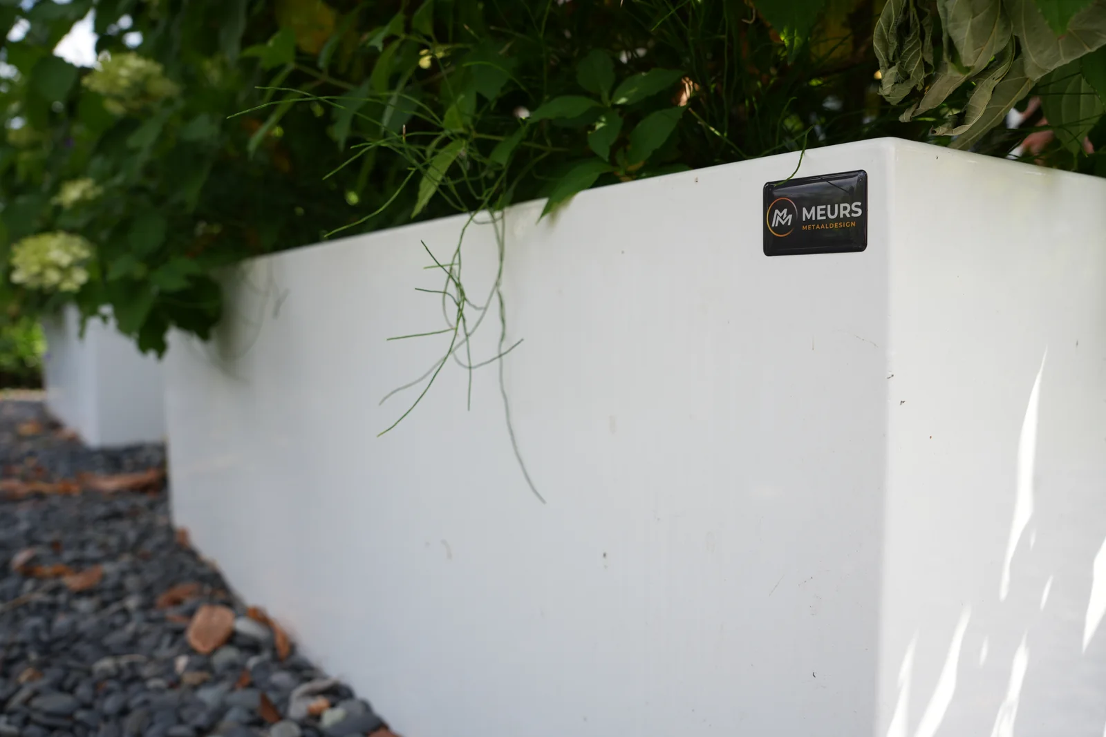Detail van een witte plantenbak met Meurs Metaaldesign-merk